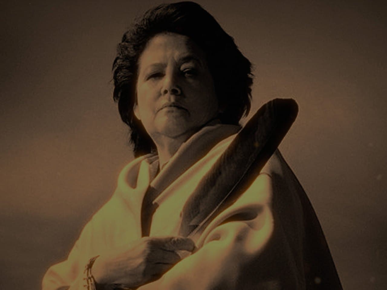 Sepia-toned portrait of Elouise Cobell holding an eagle feather